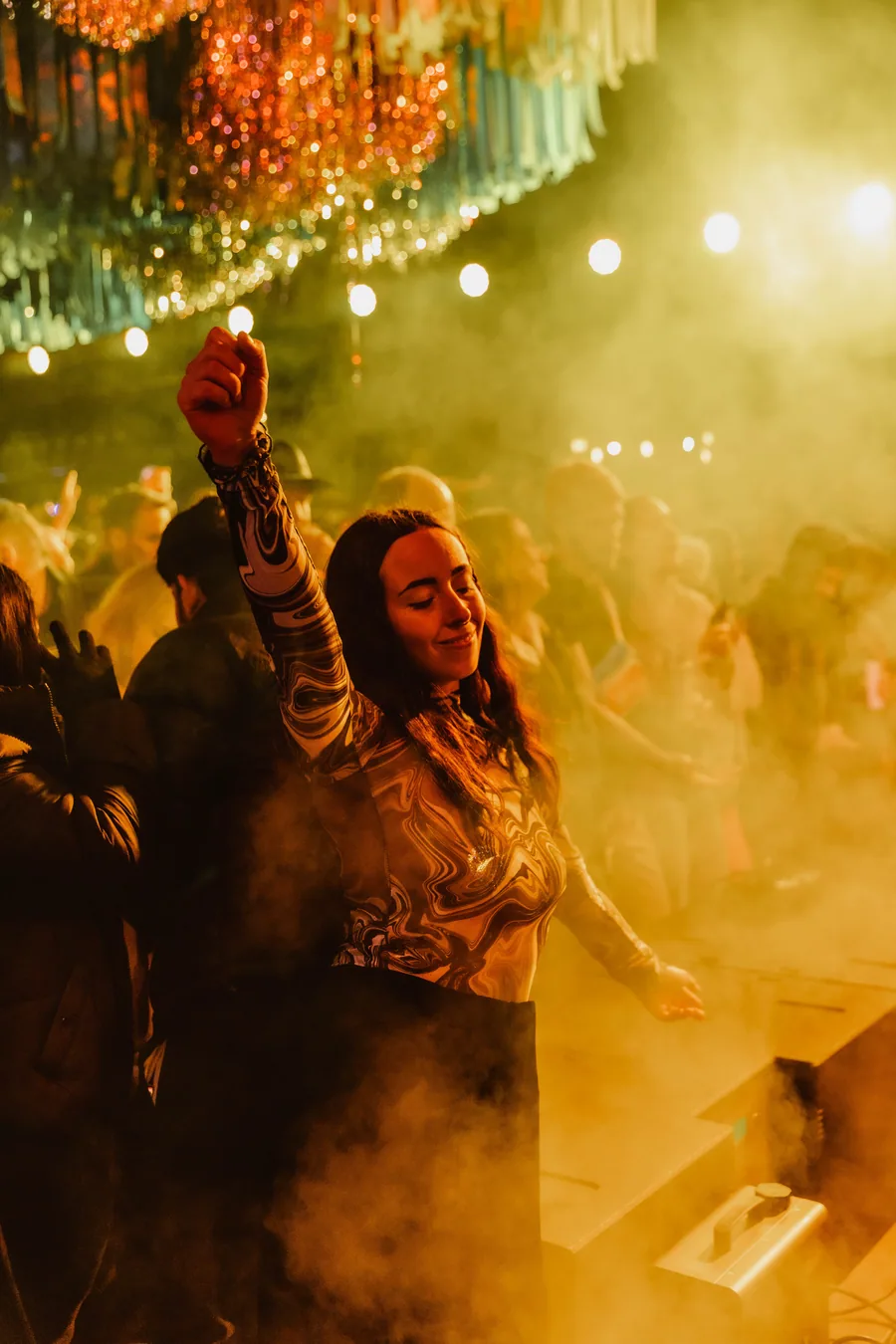 A dancer with her hand up in gold light and haze